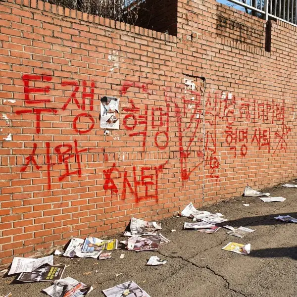 붉은색 라카 스프레이로 훼손된 대학 건물 외벽과 복구 작업을 하는 인부들의 모습