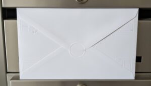 금속 우편함에 비스듬히 꽂혀 있는 깨끗한 흰색 편지 봉투